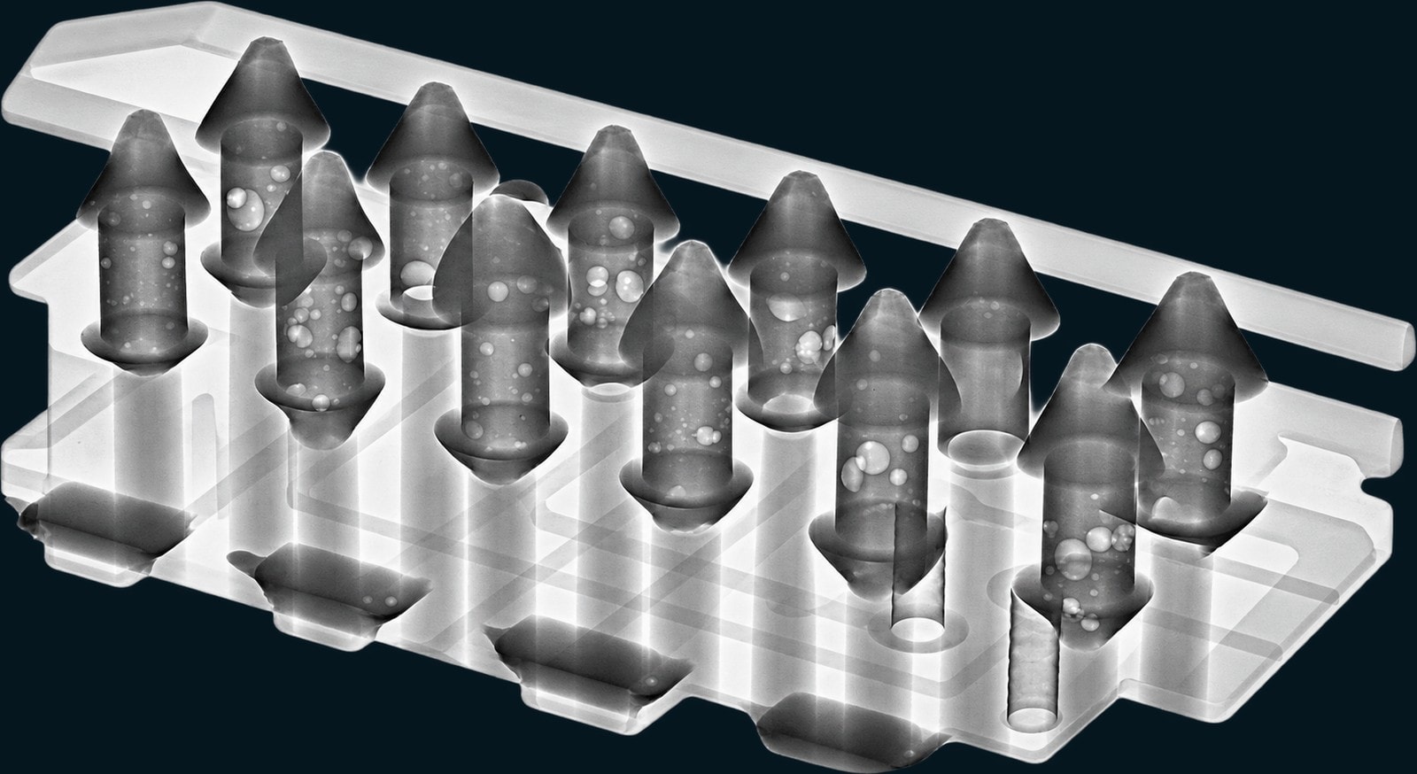 X-ray of a row of plated through-hole solder joints in a carrier, with internal voids visible as bright inclusions